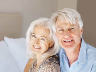 Ein älteres Paar mit Zahnimplantaten lächelt