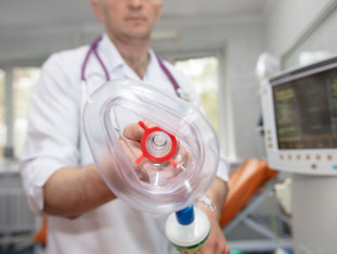 Ein Anästhesist hält eine Atemmaske zur Lachgassedierung bereit