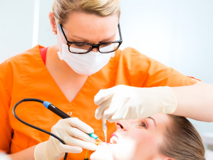 Eine Prophylaxehelferin führt an einer Patientin eine professionelle Zahnreinigung durch