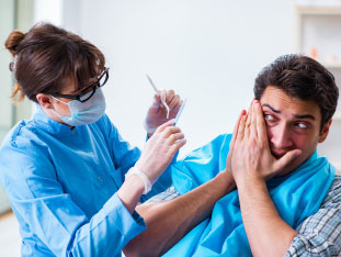Ein ängstlicher Patient hält sich den Mund zu, damit die Zahnärztin ihn nicht behandelt